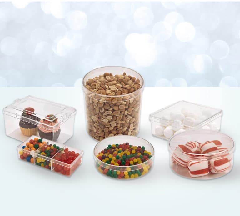 A set of clear plastic honeycomb containers displayed on a light blue surface with a blurred bokeh background and a yellow flower for added decoration. The containers, which are rectangular and square in shape, hold sections of honeycomb, showcasing the golden hues and intricate patterns. These honeycomb containers are made by Pioneer Plastics.