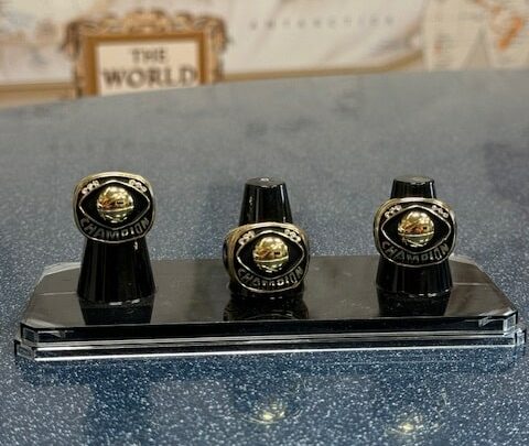 Display of three championship rings on a stand showcasing their intricate designs.
