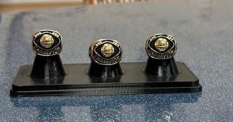 Championship rings displayed on a stand, showcasing achievements in sports history.