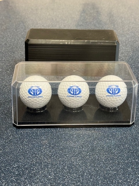 Display case featuring three branded golf balls for collectors and enthusiasts.