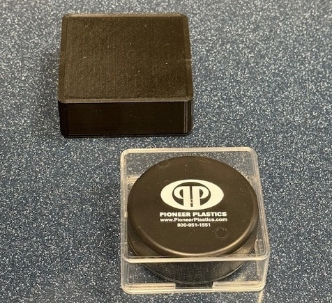 Round black plastic container for storage, featuring a clear lid and durable design.