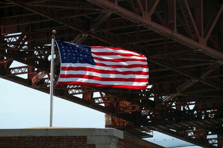 American flag fluttering gracefully beneath a bridge.