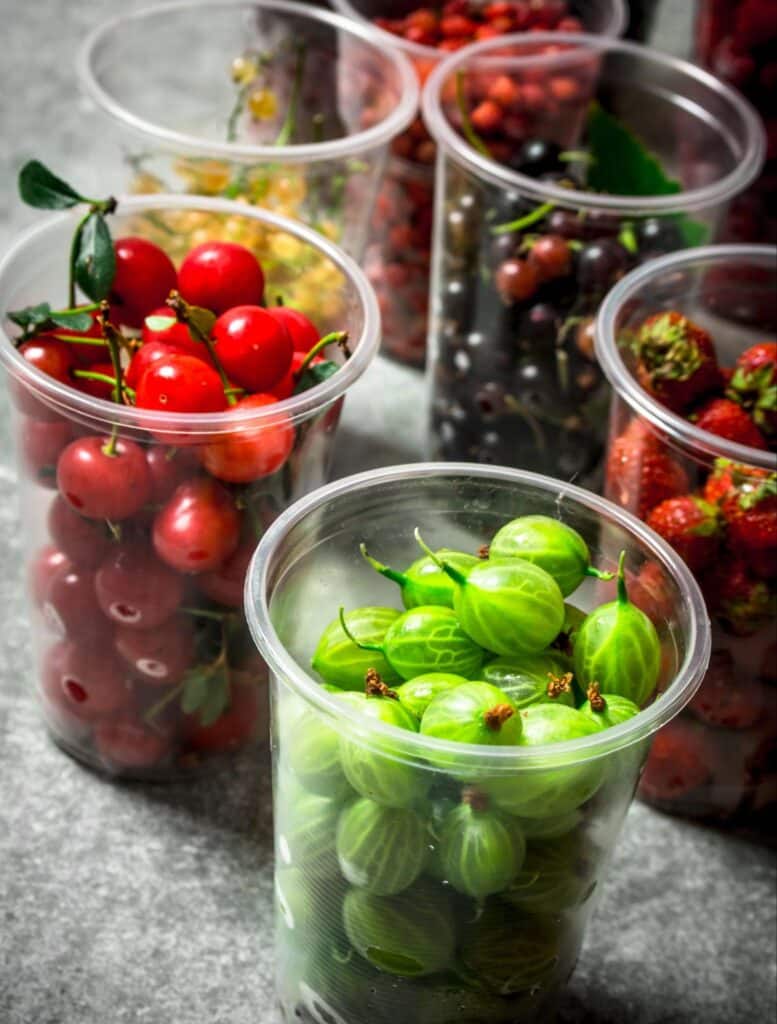 Colorful containers filled with fresh fruits, showcasing vibrant cherries, strawberries, and gooseberries.